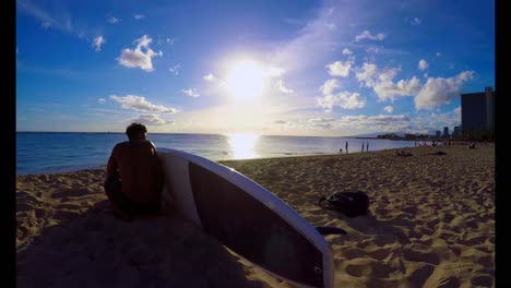 surfer with a surfboard sitting on the beach 4k