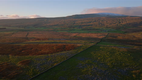 establishing aerial drone shot of snowy whernside mountain at golden hour sunset in yorkshire dales uk