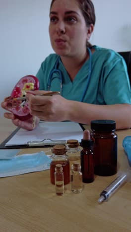 a woman in a green scrubs is holding a model of a kidney