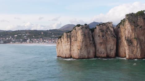 hermoso vuelo panorámico por el promontorio montagna spaccata para revelar el centro de la playa de gaeta y la ciudad frente al mar y la cordillera en el fondo, italia, antena lateral