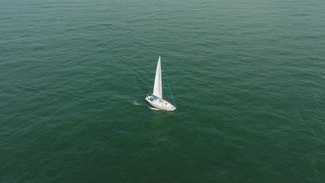 vista aérea de un velero blanco en el tranquilo mar báltico, yate de vela blanco en medio del mar sin límites, día soleado de verano, gran ojo de pájaro hecho disparo, inclinado hacia abajo