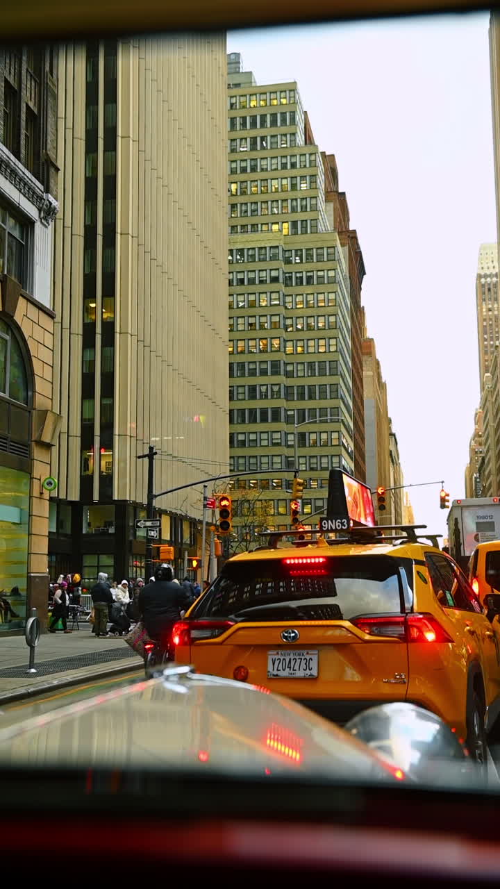 New York, USA, 28 agosto 2025: seduto in auto dietro a un taxi giallo nel traffico di New York, USA. Visuale dal basso verso l'alto sui grattacieli della metropoli. Video verticale