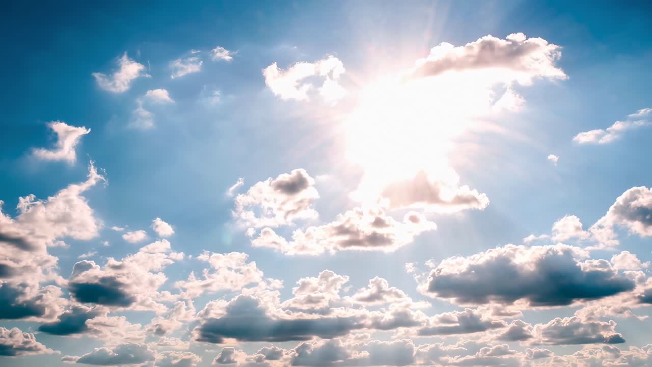 Video che cattura una vista dal basso del sole che splende tra le nuvole in un cielo blu brillante