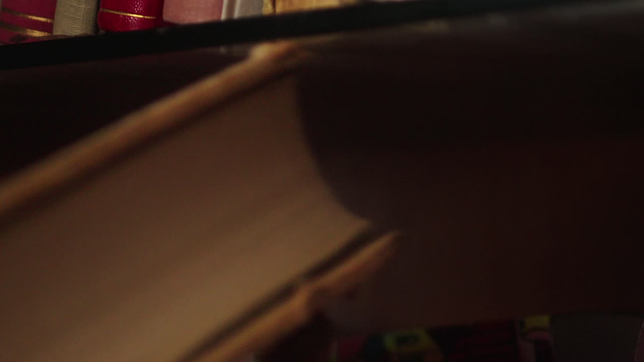 한 사람 의 손 이 도서관 에서 오래된 하드 커버 책 을 꺼내는 것