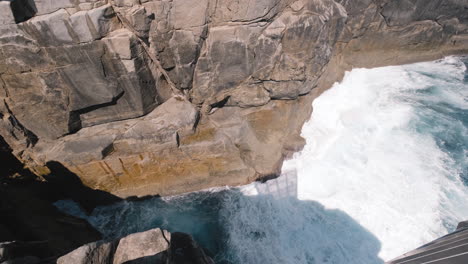 mirando hacia abajo sobre las olas golpeando los acantilados en el mirador gap, cerca de sydney, en un día soleado, en australia - cámara lenta