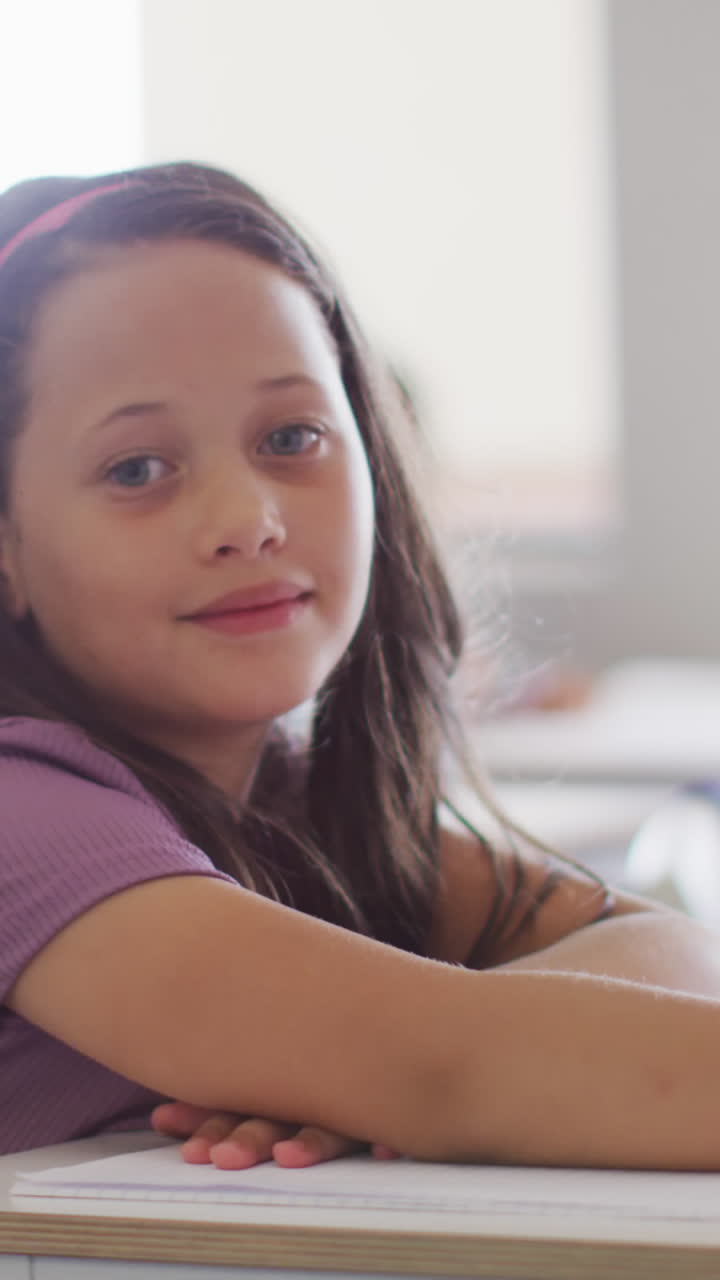 video de una chica caucásica feliz sentada en un escritorio en el aula