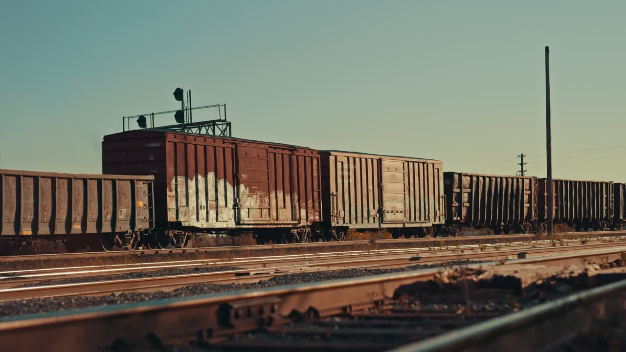 Freight Train Cargo Cars Coming to a Stop at Empty Industrial City Railway Yard. Locomotive wagons park on Station Rail Tracks Infrastructure at Sunset during Golden Hour Dusk Cinematic ProRes 4k