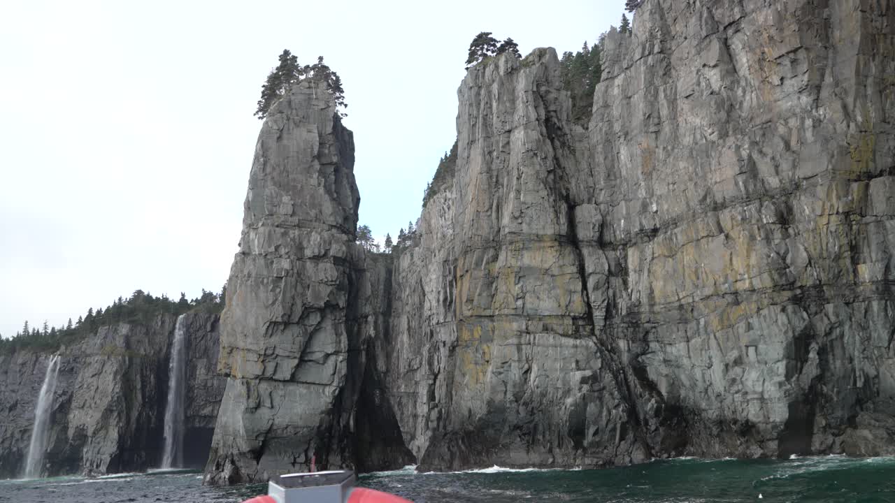 barco de excursión frente a los altos acantilados de roca en la costa de terranova canadá.