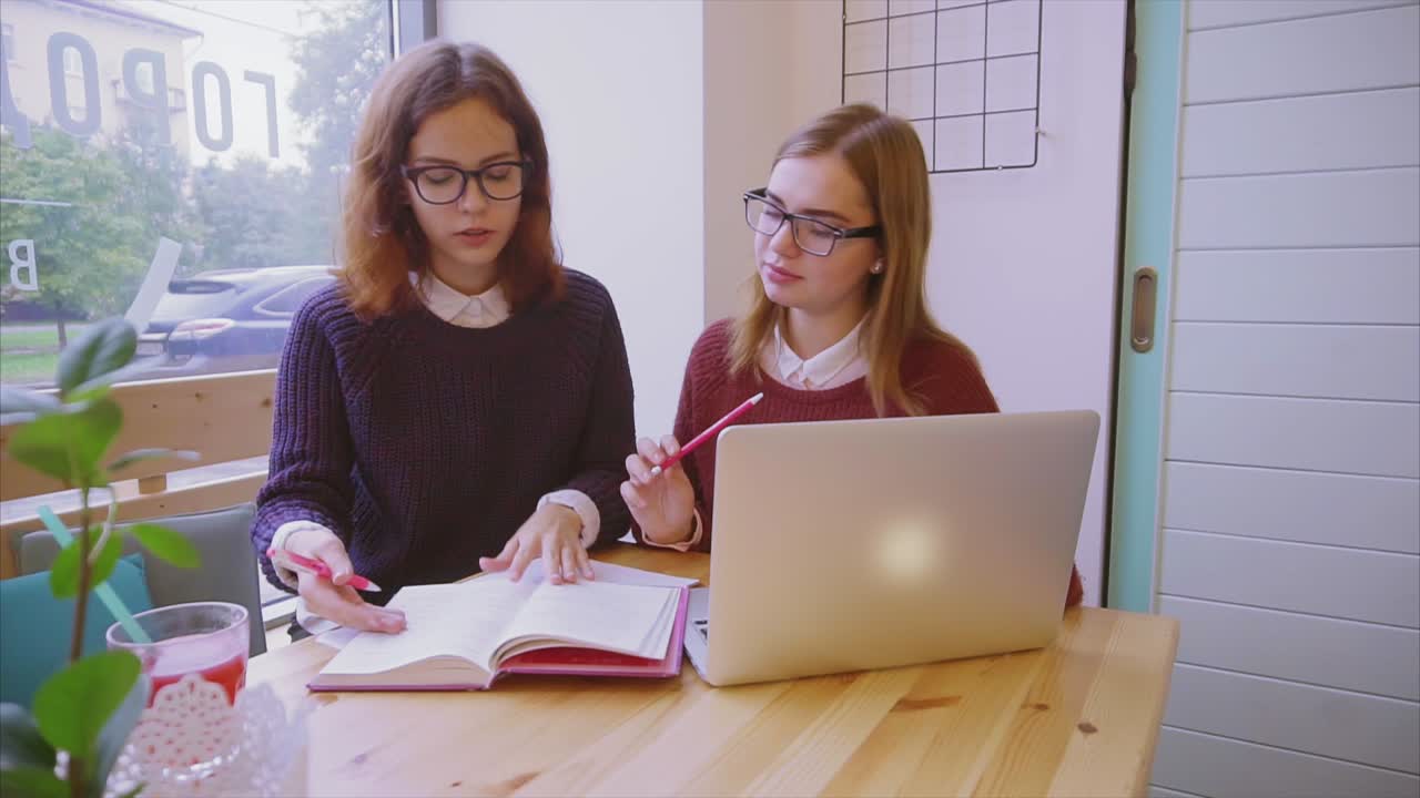 dos estudiantes estudiando en una cafetería