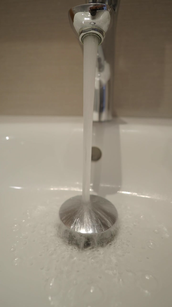 Running Water Flowing from a Chrome Faucet into a White Sink Drain