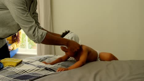 Mid-section-of-young-black-father-helping-his-son-changing-his-clothes-on-bed-in-comfortable-home-4k