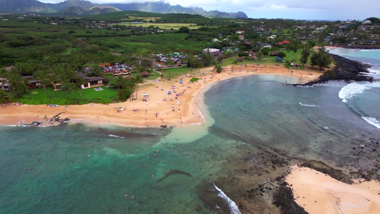 Filmato drone 4K di Poipu Beach che orbita sulla baia mentre le persone fanno snorkeling e giocano sulla spiaggia