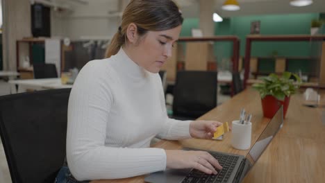 woman paying bills online in a modern co-working space.