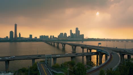 car traffic on wonhyo bridge and ramps over han river during colorful sunset in seoul downtown, yeouido 63 building yeongdeungpo district in background - real-time high angle