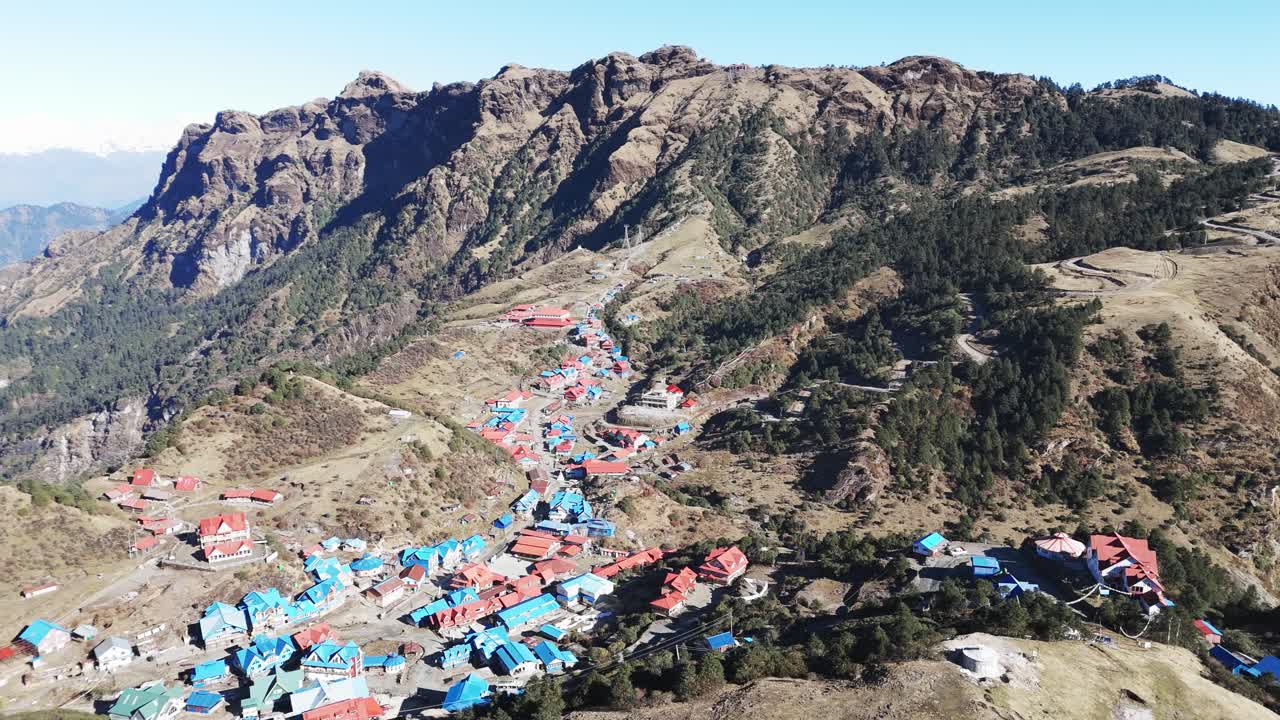 Dronebeeld van het dorp Kalinchowk in Dolakha toont huizen op een heuvel omringd door bergen en weelderig groen terrein in Nepal
