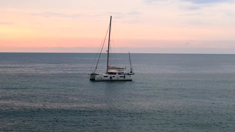 ariel drone approches a yacht in the sea at sunrise in spain