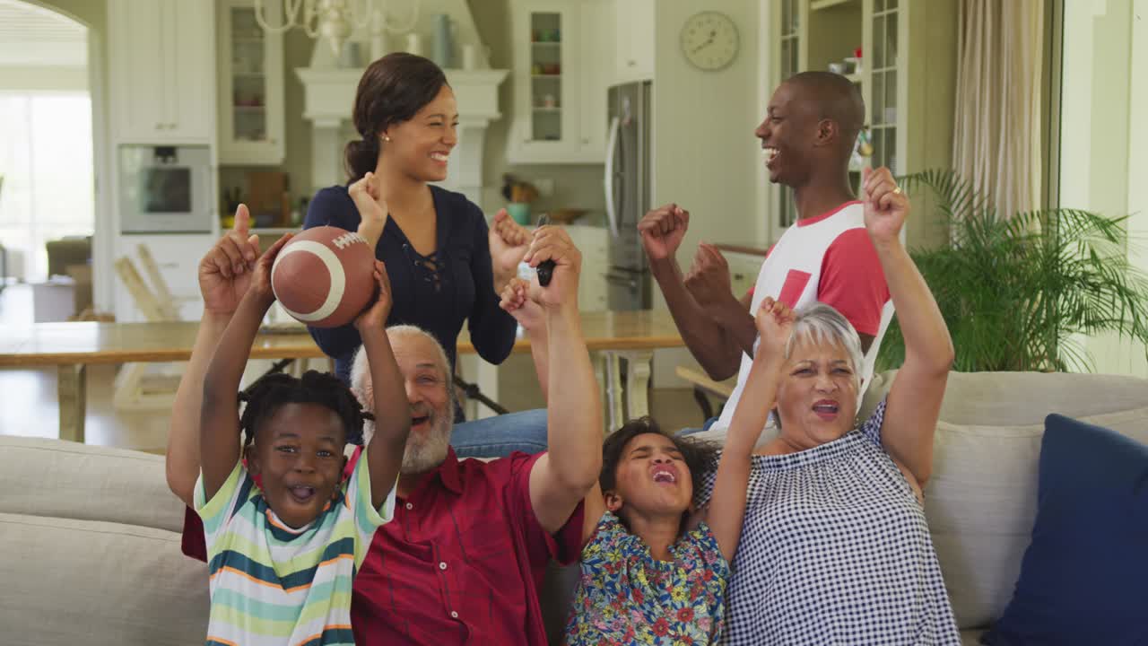 Three generation family cheering while watching TV at home