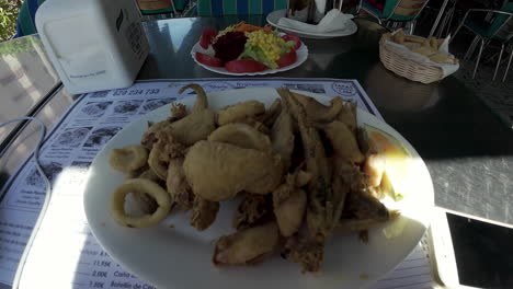 sirviendo pescado frito y calamar en el plato en un restaurante español en málaga, españa
