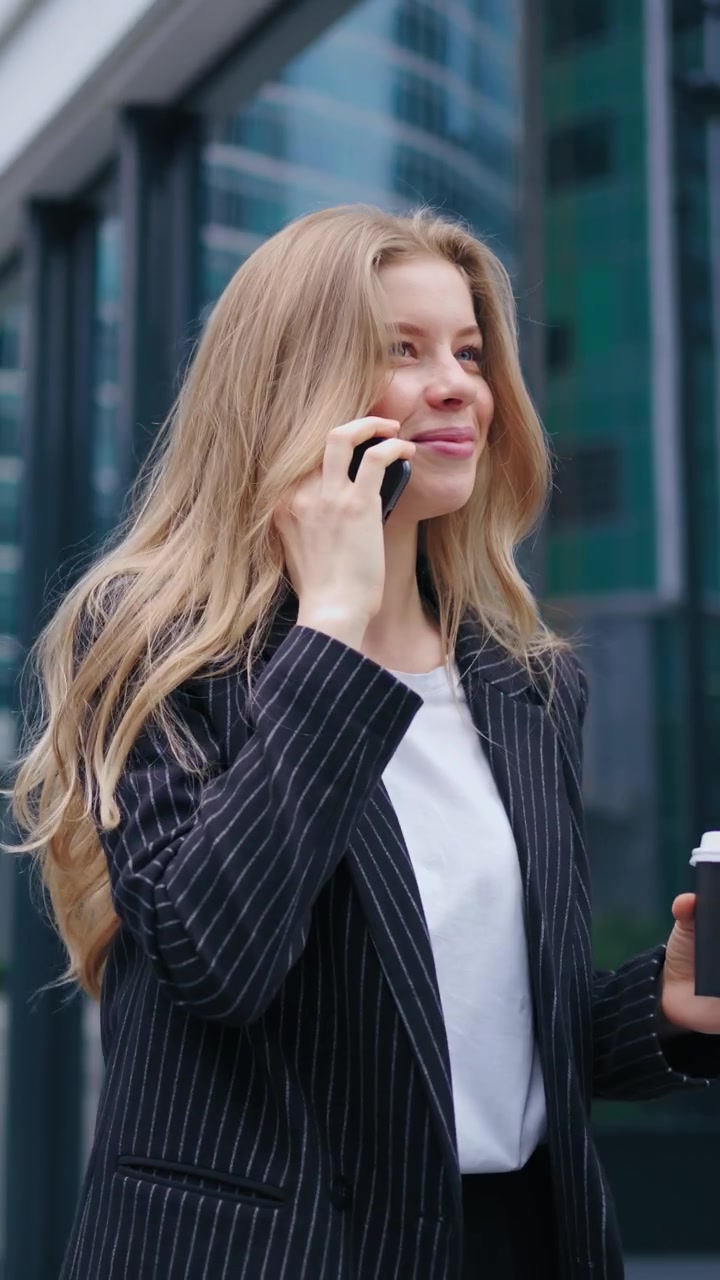 Giovane imprenditrice che parla al telefono fuori da un moderno edificio per uffici