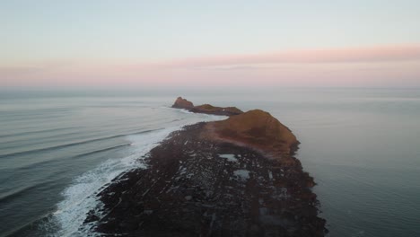 aerial: wide circle of worm's head during sunrise, rhossili gower, 4k, drone