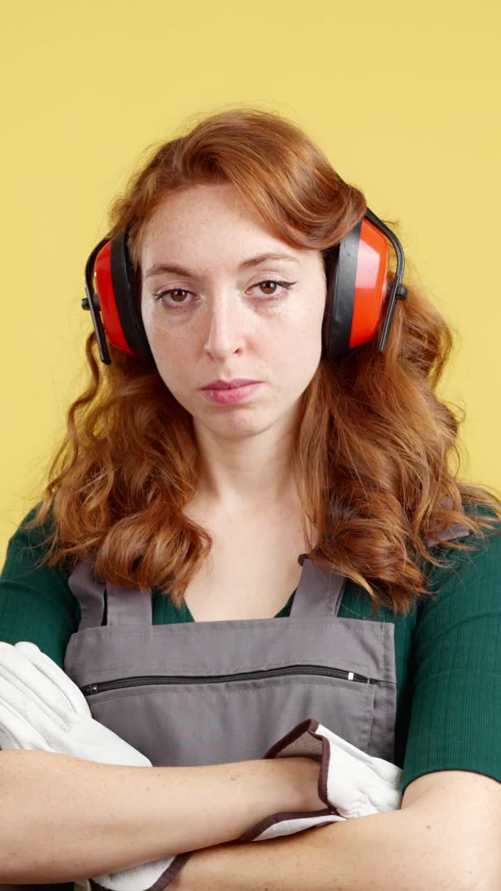 Woman in Ear Defenders and Work Overall with a Pensive Expression