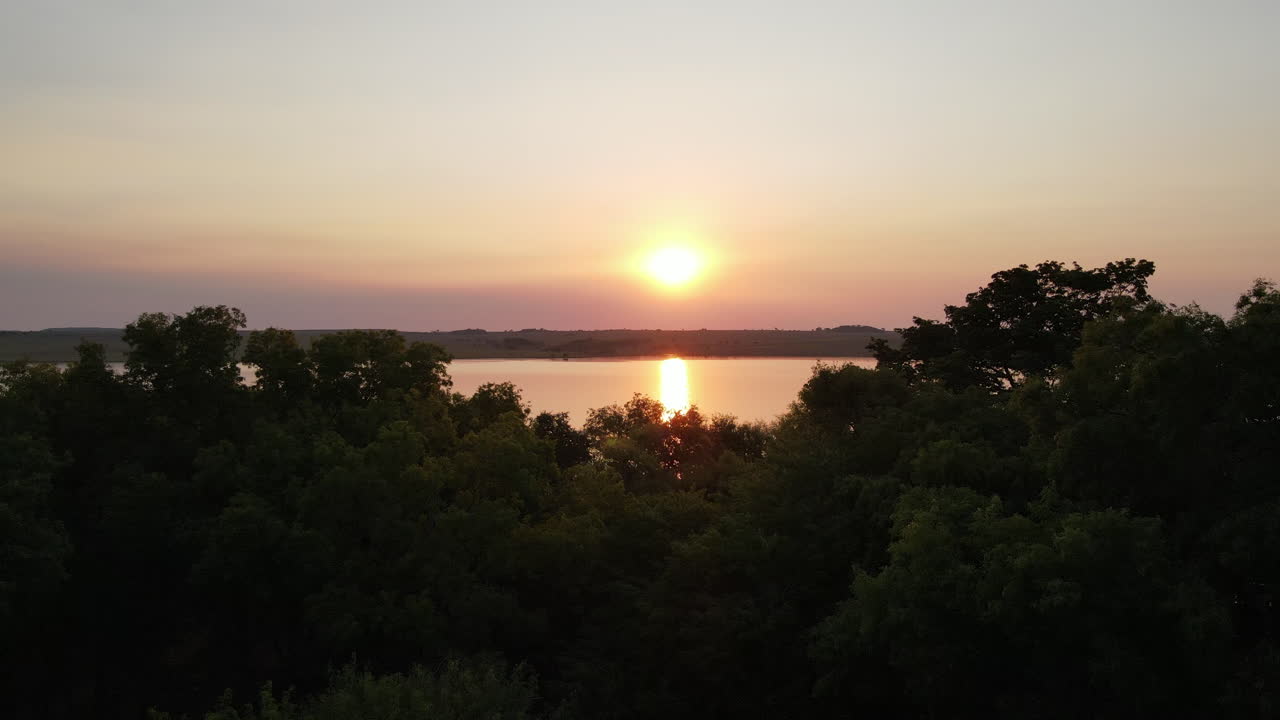 la vista aérea captura una impresionante puesta de sol en la jungla, proyectando tonos cálidos sobre un río sereno, creando una escena hipnótica y tranquila en el corazón del desierto