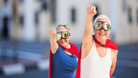 animation of happy senior caucasian couple with superhero costumes over city