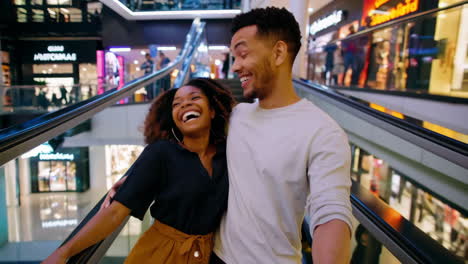 happy couple laughing on an escalator in a modern shopping mall