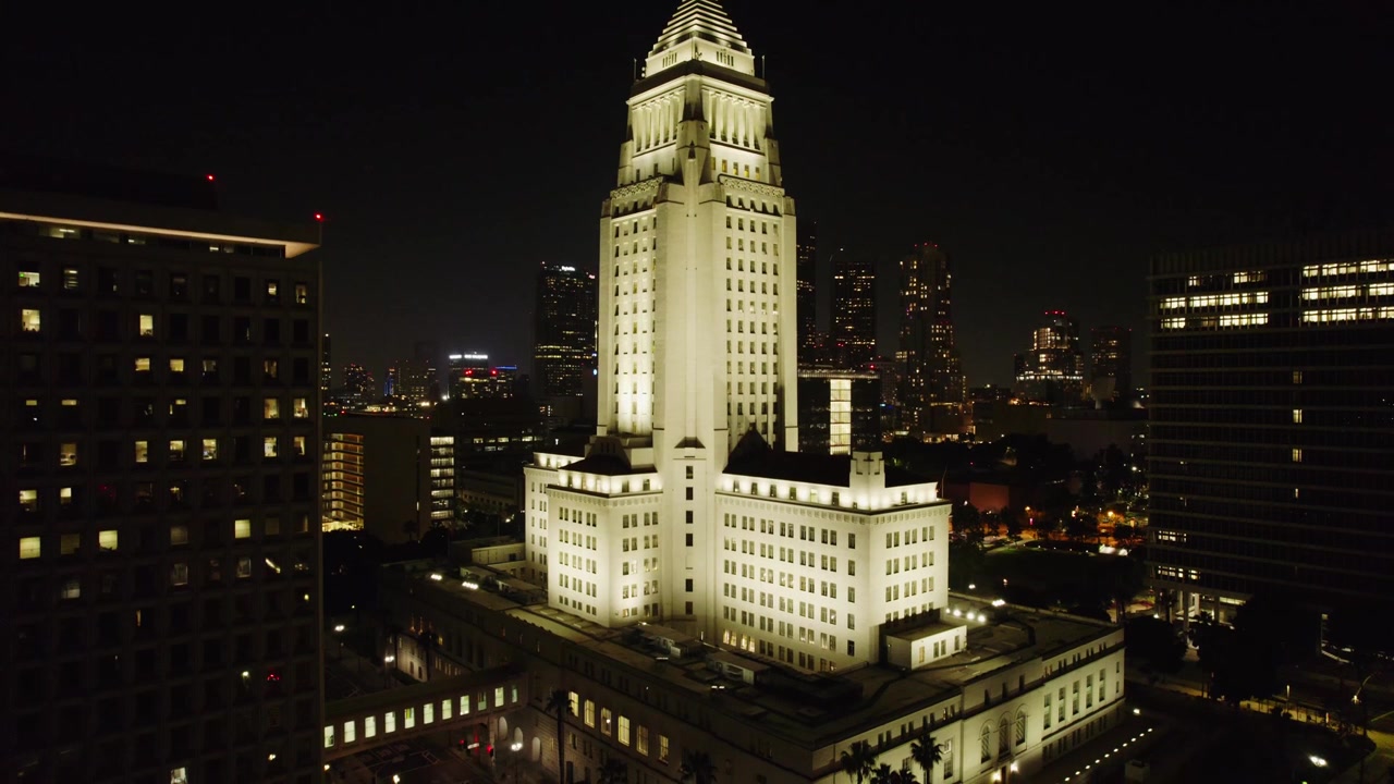 Una splendida vista aerea di Los Angeles di notte che mostra l'iconico Municipio tra le vivaci luci della città. Lo skyline illuminato dipinge un bellissimo paesaggio urbano.