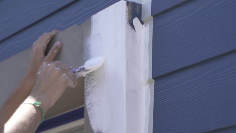 slow motion shot of male person painting window frame with brush in white color