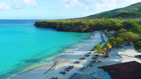 Push-in-over-cliff-to-Grote-Knip-white-sand-beach-and-clear-blue-water,-aerial