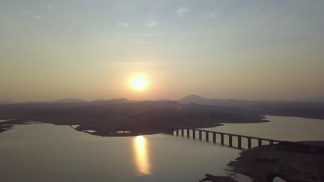 profile view of sun shining bright right before sunset in hyderabad, india with a bridge in foreground