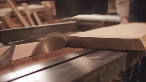 aiming footage of a circular saw in process. the carpenter is sawing the wood, making shape. wood dust. slow motion