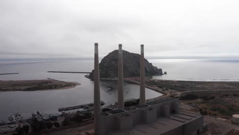 Nahaufnahme-Eines-Luftflugs-An-Den-Schornsteinen-Des-Kraftwerks-Morro-Bay-Vorbei-In-Richtung-Morro-Rock-In-Morro-Bay,-Kalifornien