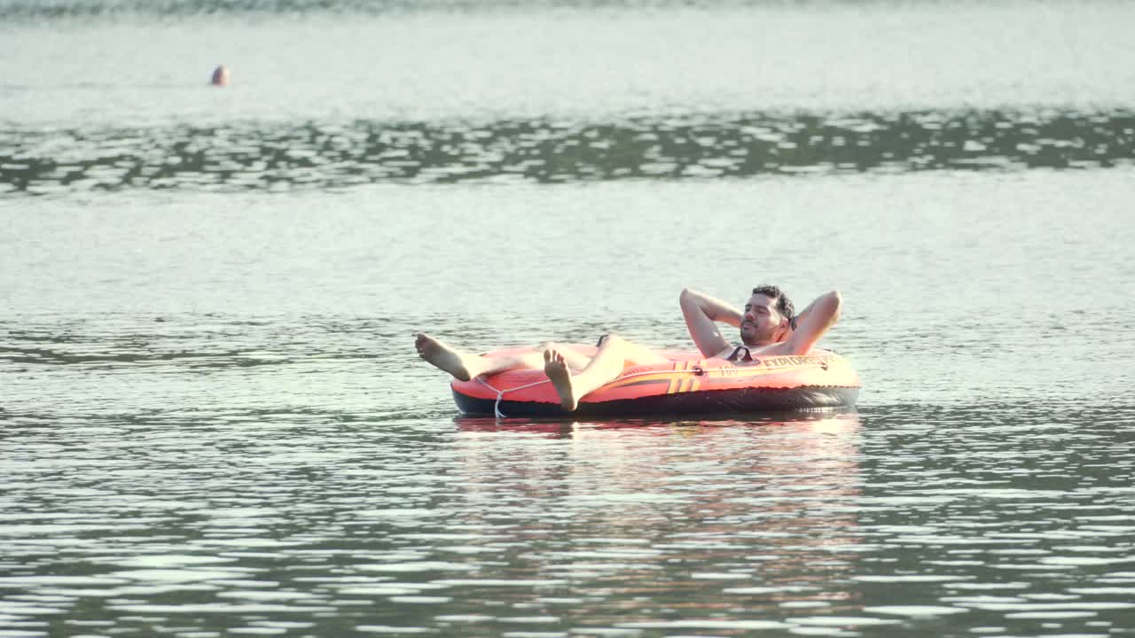 Summer holiday person relaxing on a large inflatable tube Étang de Hanau lake in France