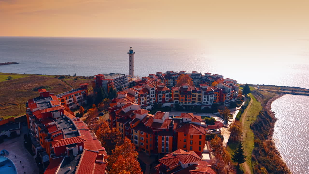 Splendidi edifici luminosi nel complesso di Marina Cape con un bellissimo faro. Vasto paesaggio acquatico del Mar Nero abbagliato dal sole al tramonto. Vista aerea