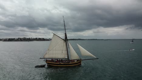 Le-Renard-Robert-Surcouf-wooden-boat-on-sea-with-cloudy-sky