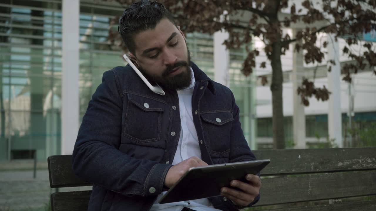Focused man using smartphone and digital tablet outdoor