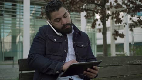 Focused man using smartphone and digital tablet outdoor