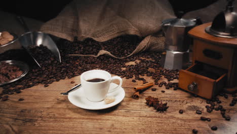 cámara moviéndose de izquierda a derecha - toma de un café recién servido frente a una bolsa de granos de café y una cafetera espresso en una mesa de madera