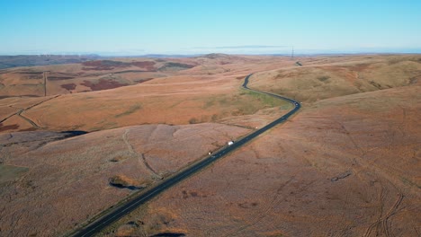 Ferne-Autos,-Die-Eine-Landstraße-In-Den-Mooren-Des-Vereinigten-Königreichs-Mit-Barron-Landschaft-Hinunterfahren