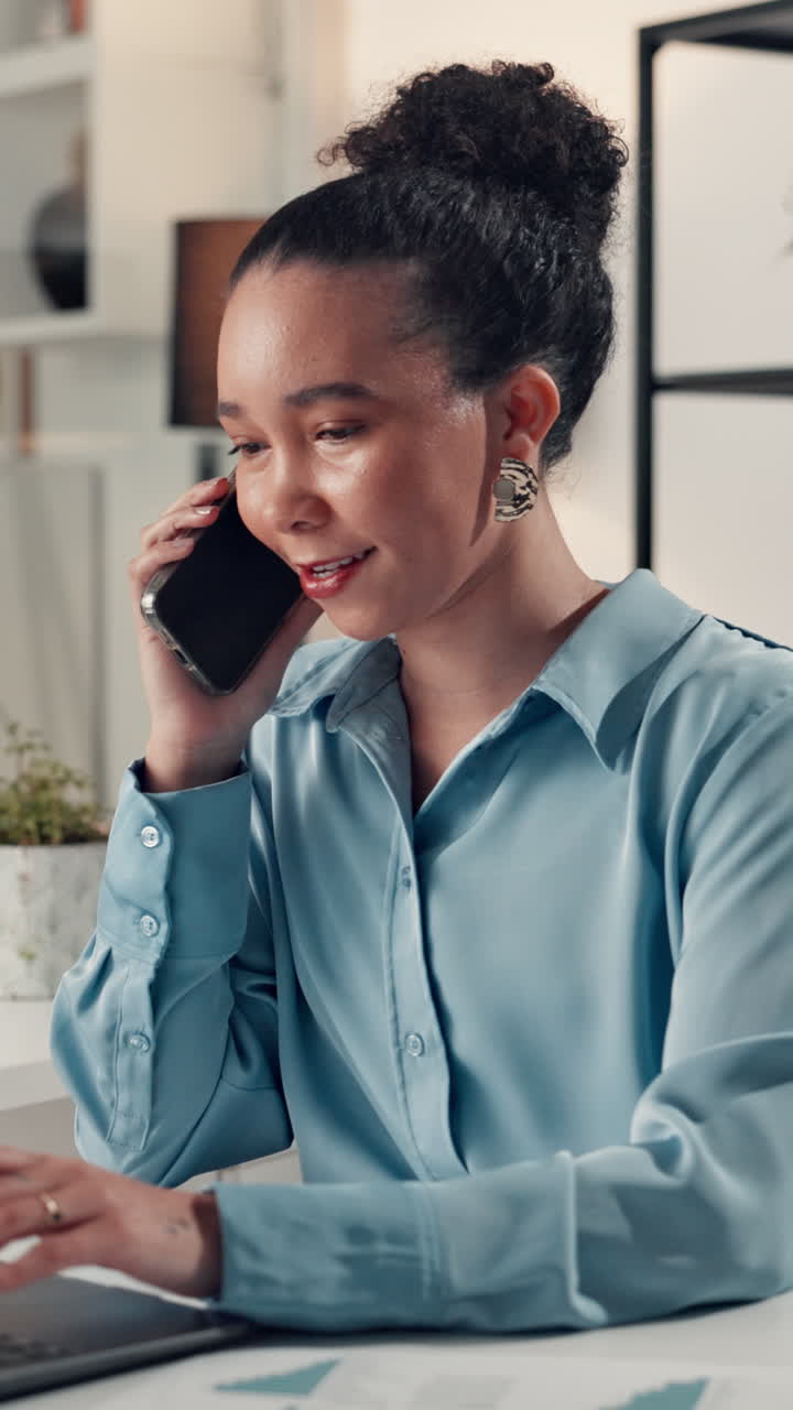 Young Woman Talking on Phone and Typing on Laptop in Office