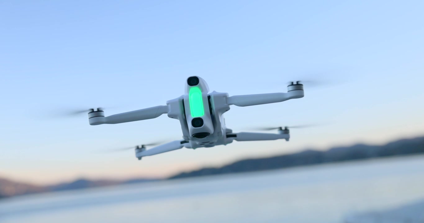 Primo piano di un drone compatto bianco che si libra a mezz'aria sull'acqua del lago al tramonto