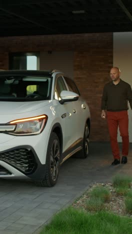 person getting into a white electric suv at home.