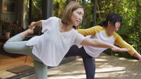 Asian-mother-and-daughter-practicing-yoga-outdoors-in-garden