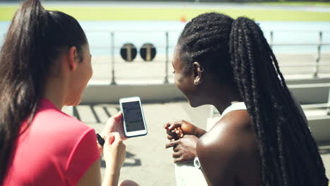 Female-athletes-laughing-while-using-phone