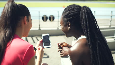atletas mujeres riendo mientras usan el teléfono