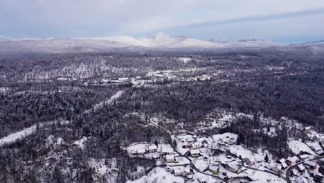 Impresionante-Vista-De-La-Zona-Rural-Cubierta-De-Nieve,-Pueblo-Y-Carretera-En-El-Bosque-De-Invierno,-Dron-De-Eslovenia