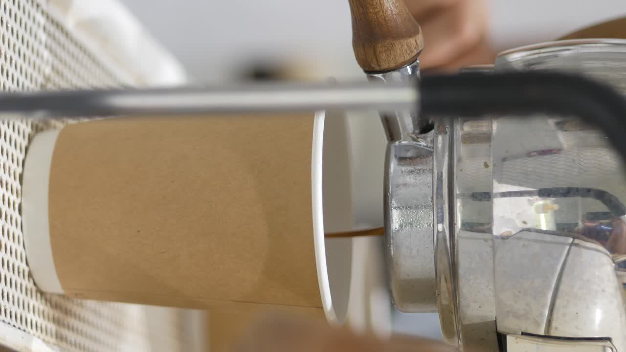 Coffee being poured into a paper cup from an espresso machine