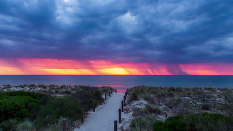 lightening bolts and rain fall over the ocean during a beautiful sunset at henley beach south